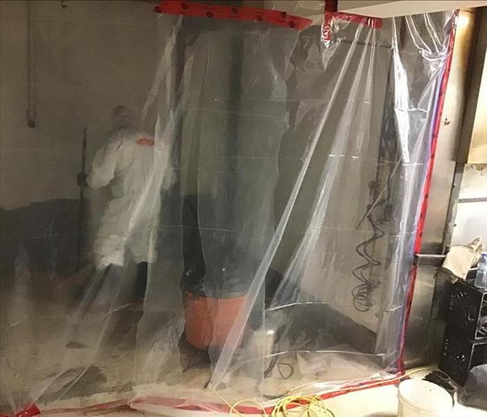 technician in a white Tyvek suit, containment in place, working