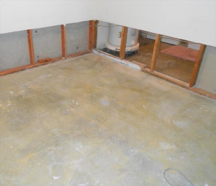 bear concrete pad, opened wall showing studs and water heater