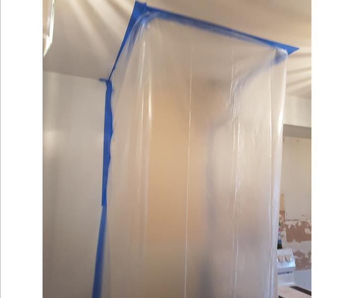 transparent poly sheeting with blue painters tape enclosing a wall a part of a ceiling