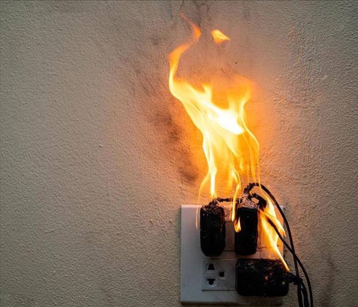 flames from a plug  -in at a socket on a wall