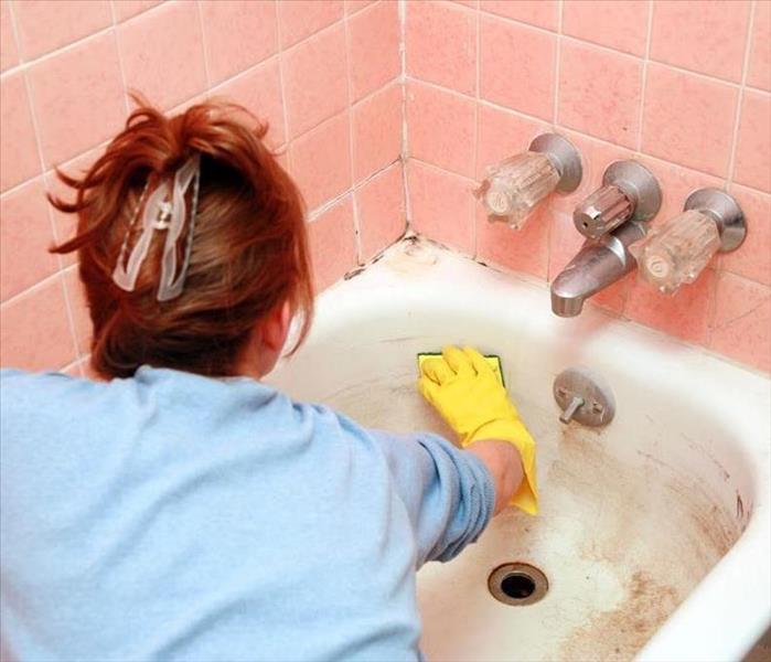Woman cleaning dirty bathtub